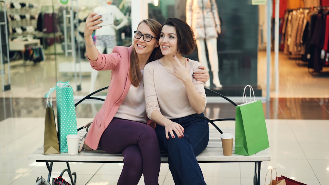 Two smiling women taking a selfie in a shopping mall.