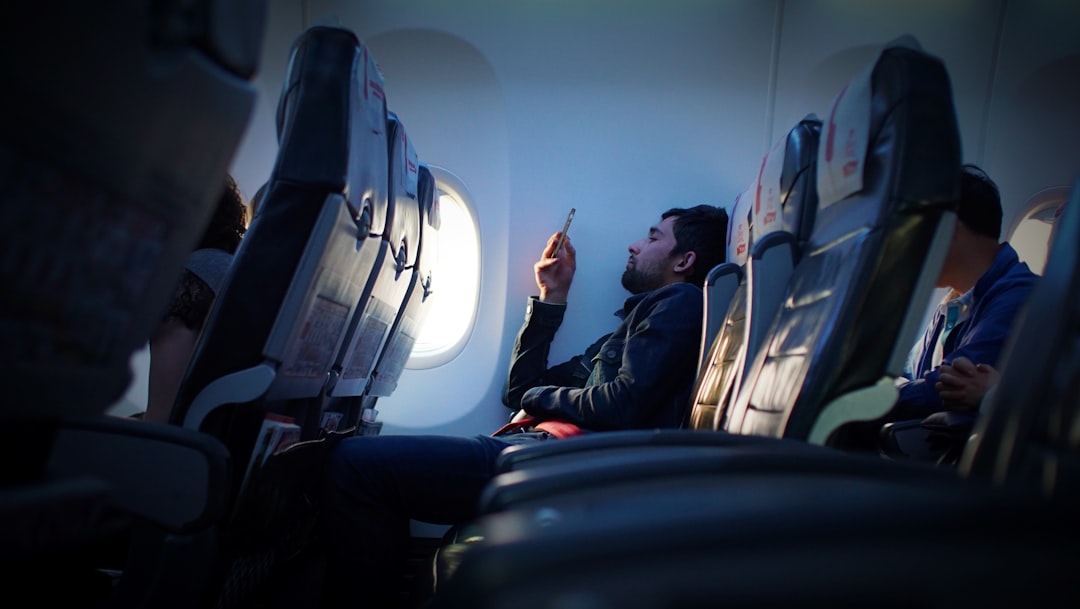 Traveler using smartphone on airplane for booking and itinerary